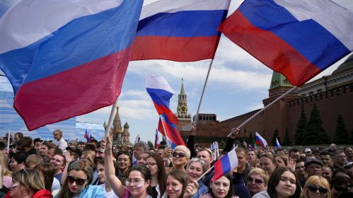 Тысячи людей размахивают российскими национальными флагами на Красной площади, придя на концерт, посвященный Дню России. День России ежегодно отмечается 12 июня. Москва, Россия. 11 июня 2023 года