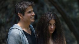 Kadr z serialu „Kotka” przedstawia dwójkę bohaterów stojących razem w otoczeniu przyrody. Mężczyzna uśmiecha się, sprawiając wrażenie pogodnego i pełnego nadziei, natomiast kobieta obok niego ma poważniejszy, zamyślony wyraz twarzy. Kontrast między ich emocjami dodaje scenie głębi, a naturalne światło i leśne tło tworzą nastrojowy, intymny klimat.