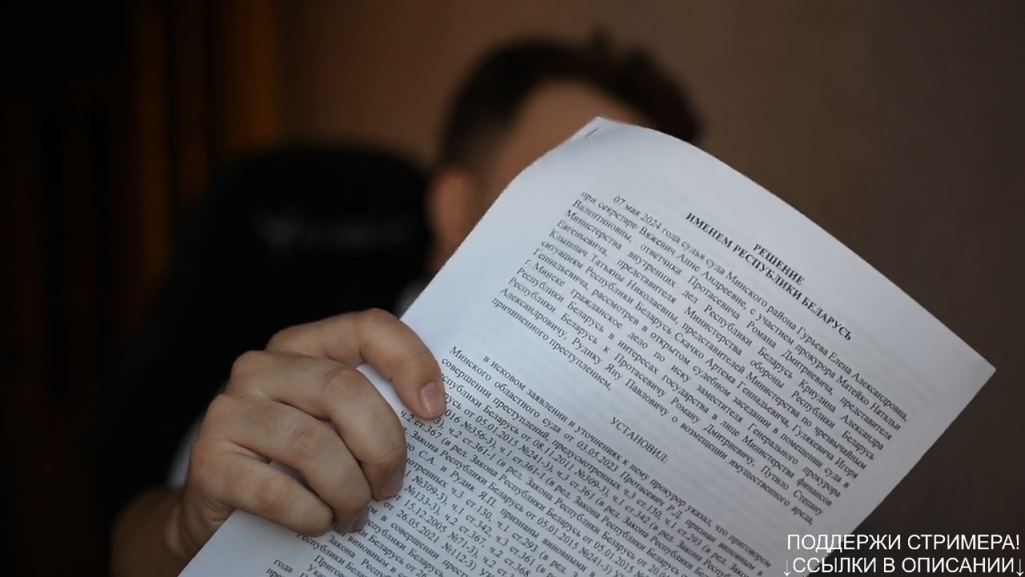 Раман Пратасевіч паказвае пастанову суду. (Фота: скрыншот з канала «Рома говорит» / YouTube)