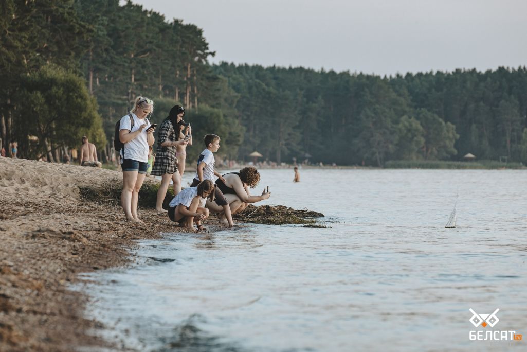 Дзеці кідаюць каменне ў ваду на пляжы на Менскім моры. Менск, Беларусь. 19 жніўня 2022 года. (Фота: Белсат)