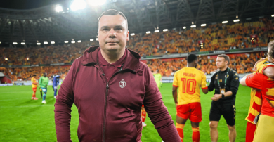 Adrian Siemieniec, trener Jagiellonii Białystok (fot. Getty). Trener Jagiellonii Białystok Adrian Siemieniec stoi na murawie stadionu, prawdopodobnie po meczu lub podczas rozgrzewki, ubrany w bordową bluzę z kapturem i zamkiem błyskawicznym. Patrzy prosto w kamerę. W tle widoczni są inni piłkarze (jeden w żółto-czerwonej koszulce z numerem 10 i napisem "PULULU") oraz trybuny wypełnione kibicami w żółto-czerwonych barwach (fot. Getty).